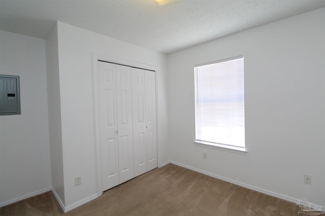 unfurnished bedroom with electric panel, a closet, carpet flooring, and a textured ceiling