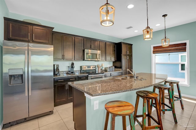 kitchen with dark stone countertops, sink, dark brown cabinetry, decorative light fixtures, and appliances with stainless steel finishes