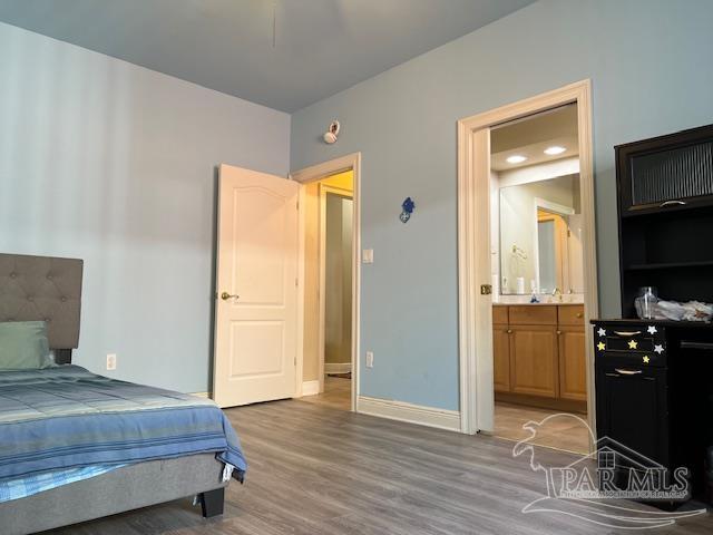 bedroom with ensuite bath and hardwood / wood-style flooring