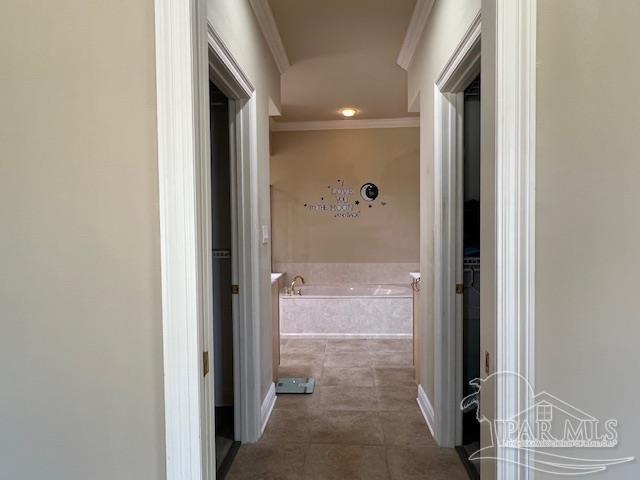 corridor with dark tile patterned flooring and crown molding