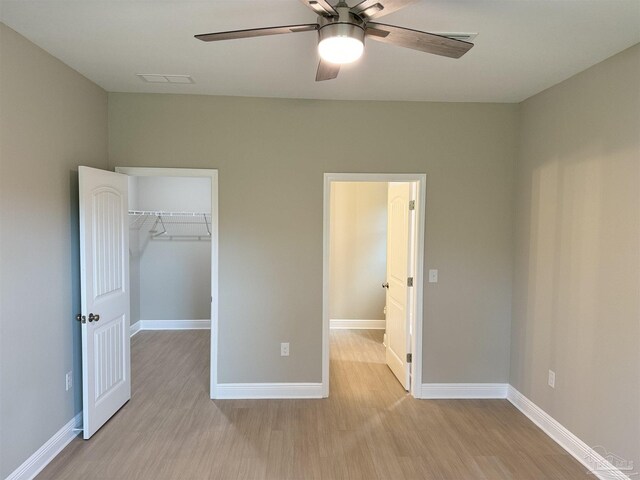 empty room with a textured ceiling, ceiling fan with notable chandelier, and light hardwood / wood-style flooring