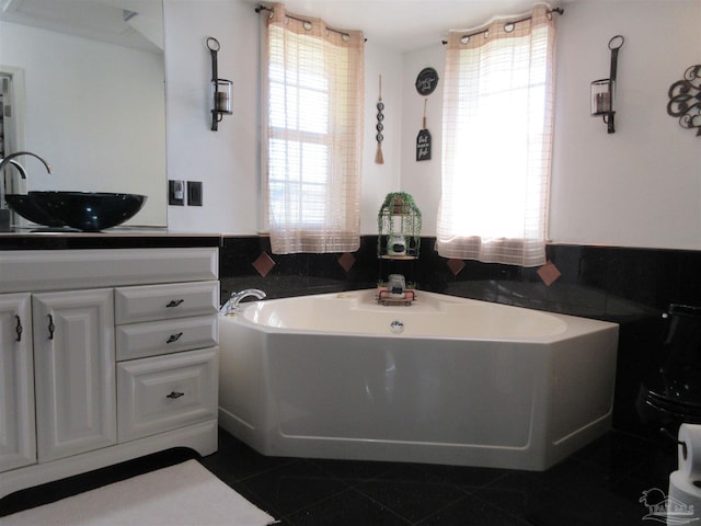 bathroom with a washtub, vanity, and tile patterned floors