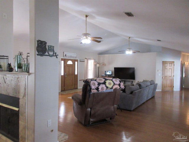 living room featuring a premium fireplace, lofted ceiling, and wood-type flooring