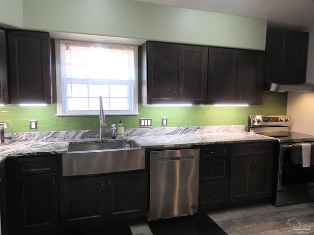 kitchen with light stone countertops, appliances with stainless steel finishes, sink, and backsplash