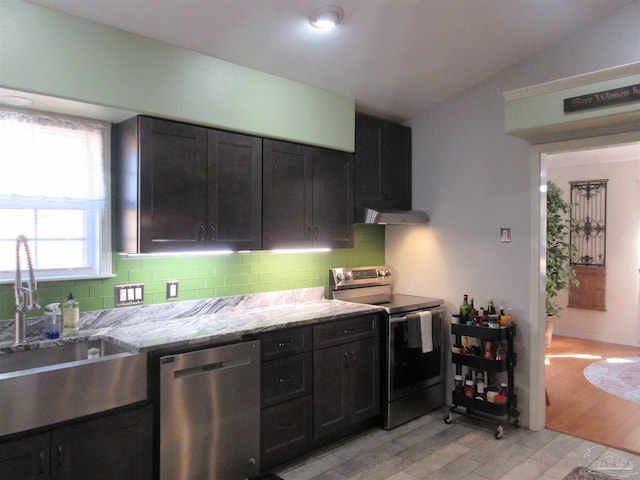 kitchen featuring tasteful backsplash, sink, light stone counters, stainless steel appliances, and light hardwood / wood-style flooring