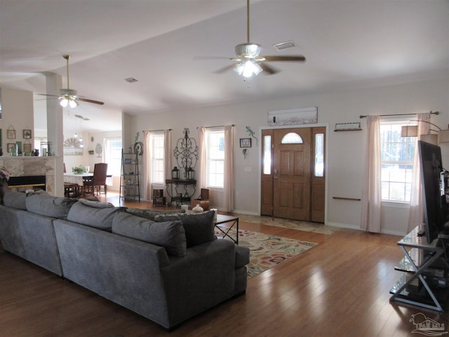 living room with vaulted ceiling, dark hardwood / wood-style floors, a high end fireplace, and ceiling fan