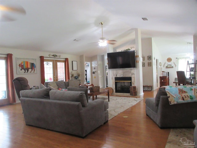 living room with hardwood / wood-style flooring, lofted ceiling, a high end fireplace, and french doors