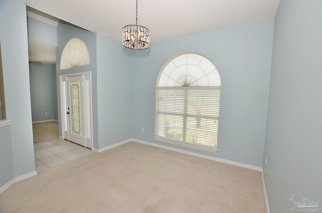 carpeted spare room featuring an inviting chandelier