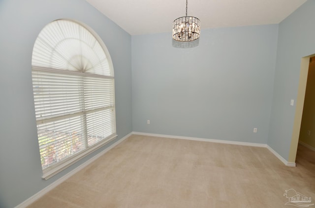 carpeted empty room with a notable chandelier