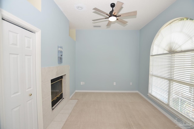 unfurnished living room with light carpet, a high end fireplace, and ceiling fan