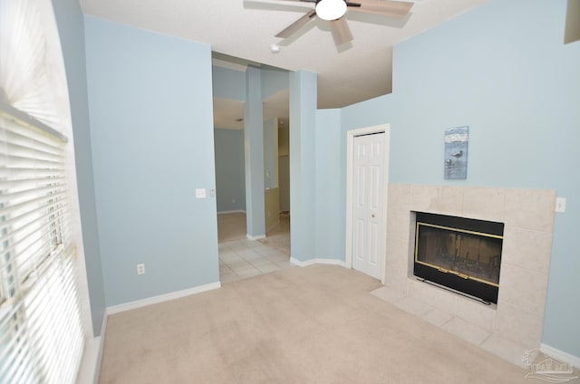 unfurnished living room featuring light carpet, a tiled fireplace, and ceiling fan