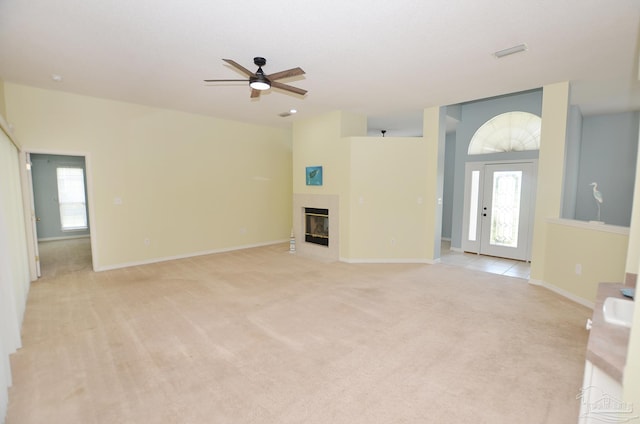 unfurnished living room featuring ceiling fan, a wealth of natural light, and light colored carpet