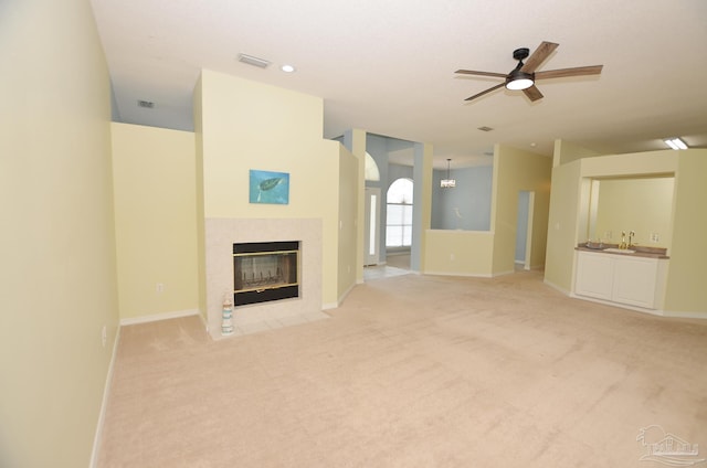 unfurnished living room with a fireplace, light colored carpet, and ceiling fan