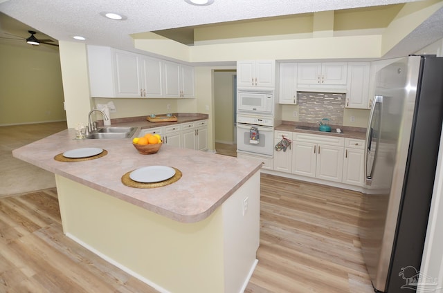 kitchen featuring light hardwood / wood-style flooring, white appliances, sink, kitchen peninsula, and ceiling fan