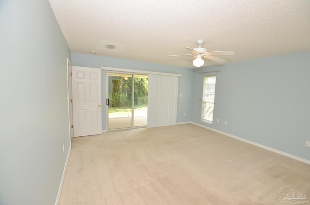 spare room featuring a textured ceiling, light colored carpet, and ceiling fan