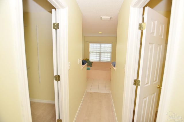 hallway with light carpet and a textured ceiling