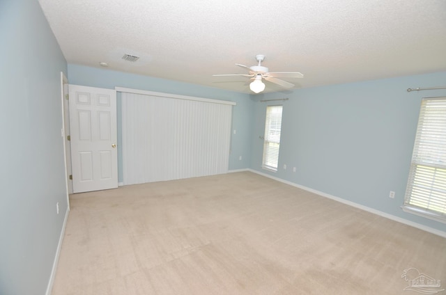 unfurnished room featuring light carpet, ceiling fan, and a textured ceiling