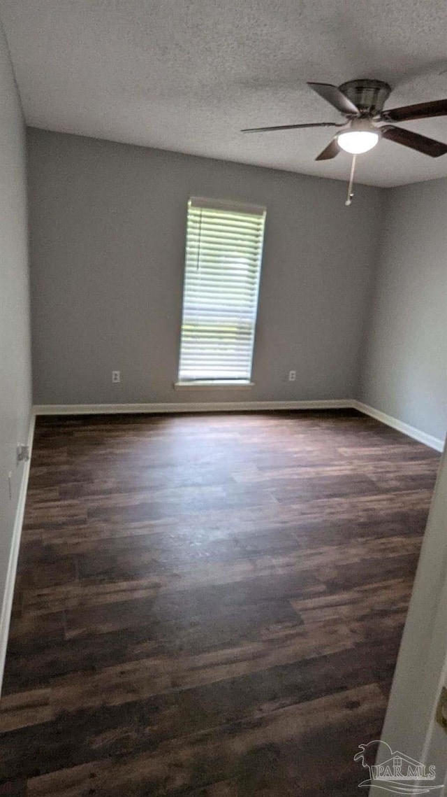 unfurnished room with ceiling fan, dark wood-type flooring, and a textured ceiling