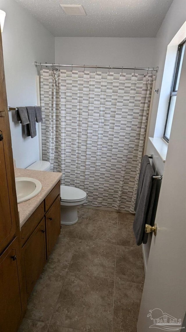 bathroom with vanity, a textured ceiling, toilet, and walk in shower