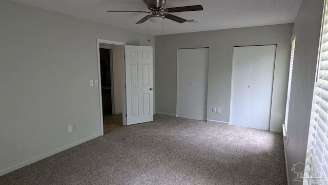 unfurnished bedroom with multiple closets, ceiling fan, and carpet