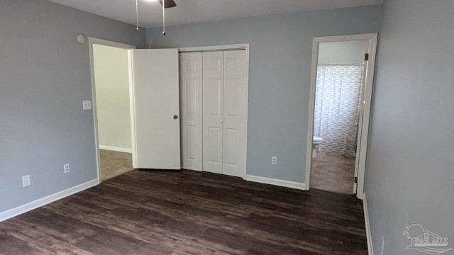 unfurnished bedroom featuring dark wood-type flooring, ceiling fan, ensuite bathroom, and a closet