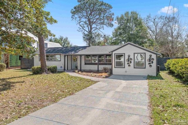 ranch-style home with concrete driveway, fence, and a front lawn