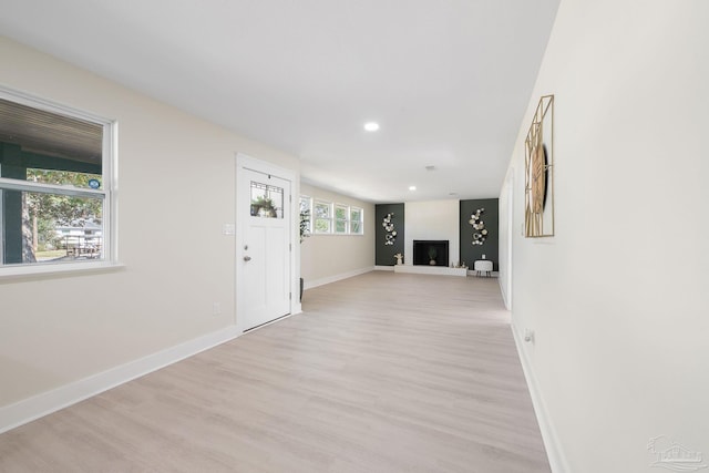 entrance foyer with light wood-type flooring, a fireplace with raised hearth, baseboards, and recessed lighting