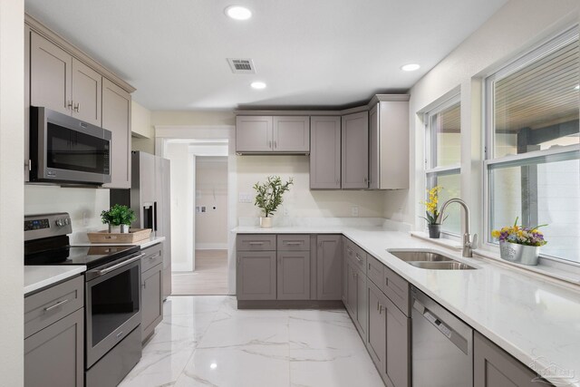 kitchen with marble finish floor, gray cabinets, visible vents, appliances with stainless steel finishes, and a sink