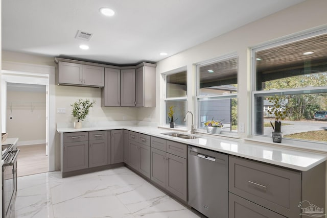 kitchen with a sink, visible vents, marble finish floor, light countertops, and appliances with stainless steel finishes