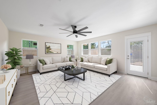 living area featuring light wood-style floors, visible vents, and a ceiling fan