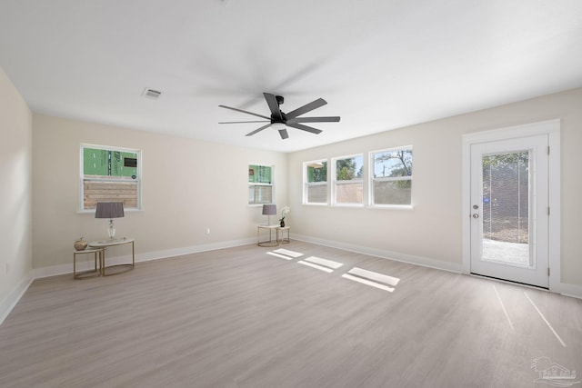 empty room featuring light wood-type flooring, ceiling fan, visible vents, and baseboards