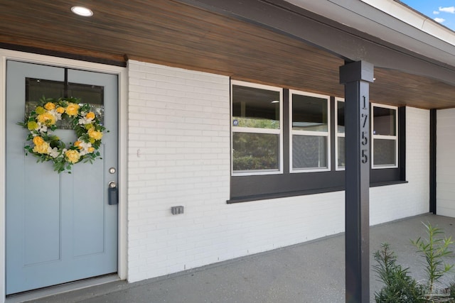 doorway to property with brick siding and a porch