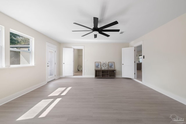 interior space with ceiling fan, light wood-type flooring, visible vents, and baseboards