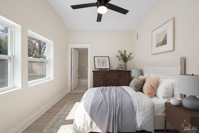 bedroom with visible vents, light wood-style floors, connected bathroom, vaulted ceiling, and baseboards