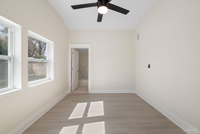 unfurnished room featuring light wood finished floors, visible vents, baseboards, and vaulted ceiling