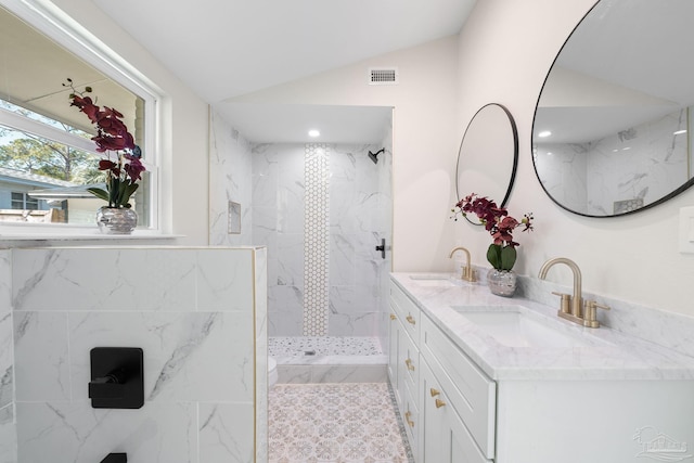 bathroom featuring lofted ceiling, double vanity, a marble finish shower, and a sink