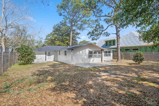 rear view of property with a lawn, a patio area, and a fenced backyard