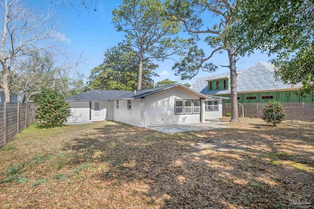 rear view of house with a patio, a lawn, and a fenced backyard