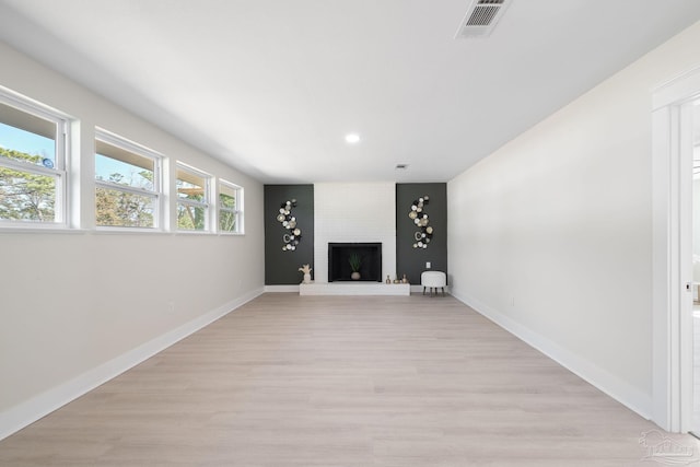 unfurnished living room featuring light wood finished floors, visible vents, a fireplace, and baseboards