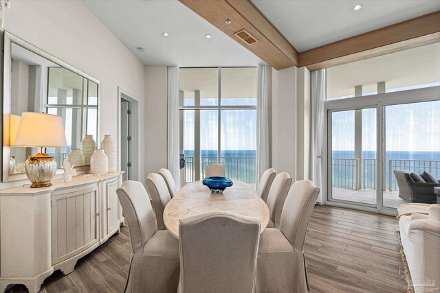 dining area featuring a wall of windows, plenty of natural light, hardwood / wood-style floors, and a water view