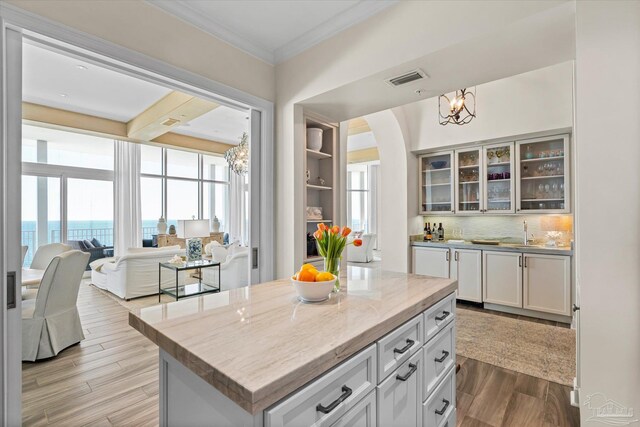 kitchen featuring a kitchen island, light hardwood / wood-style flooring, a notable chandelier, a water view, and decorative backsplash