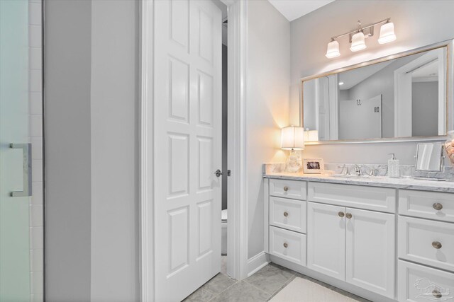 bathroom featuring tile patterned flooring, a shower with shower door, vanity, and toilet