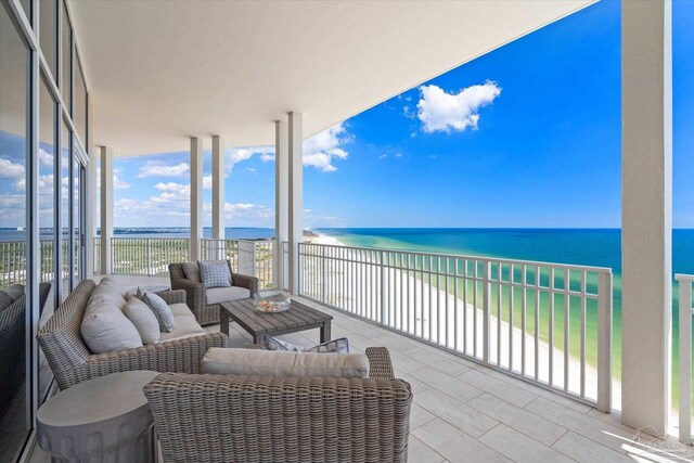 balcony featuring outdoor lounge area, a water view, and a beach view