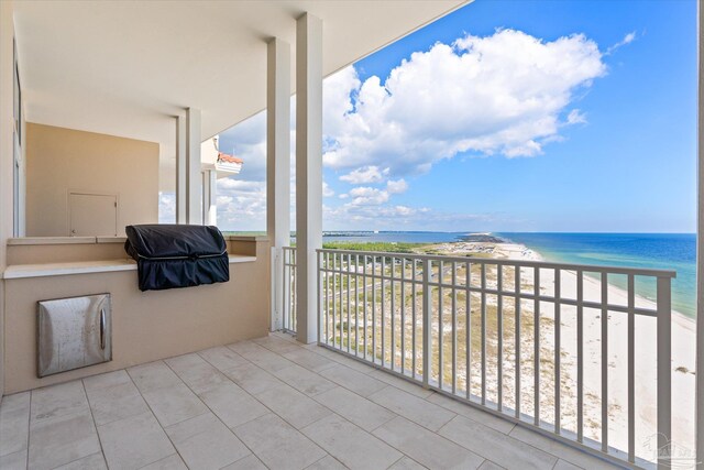 balcony featuring a water view, a beach view, and grilling area