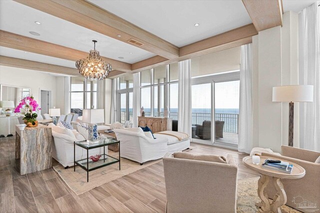 living room with an inviting chandelier, beamed ceiling, light hardwood / wood-style floors, and a water view