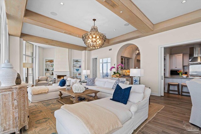 living room featuring a notable chandelier, beamed ceiling, dark wood-type flooring, and built in shelves