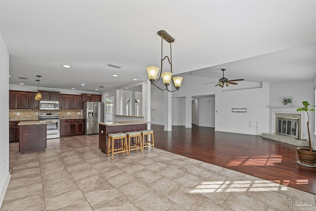 4810 Endeavor Ct, Milton, FL 32570 - kitchen with appliances with stainless steel finishes, ceiling fan, decorative backsplash, open floor plan, and a high end fireplace