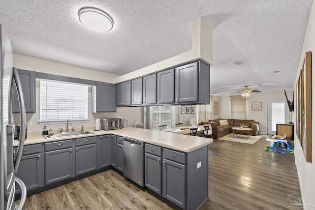 5576 Shadow Shore Pl, Gulf Breeze, FL 32563 - kitchen with stainless steel appliances, gray cabinets, a textured ceiling, a peninsula, and dark wood-type flooring