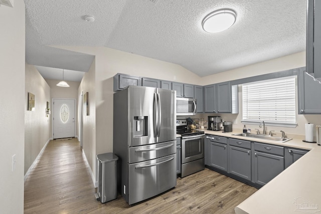 5576 Shadow Shore Pl, Gulf Breeze, FL 32563 - kitchen featuring appliances with stainless steel finishes, vaulted ceiling, wood finished floors, gray cabinets, and light countertops