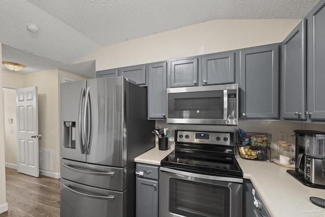 5576 Shadow Shore Pl, Gulf Breeze, FL 32563 - kitchen with stainless steel appliances, light countertops, vaulted ceiling, wood finished floors, and gray cabinets